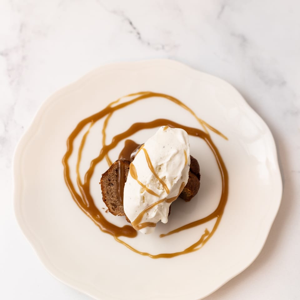 Chocolate dessert topped with vanilla ice cream and drizzled with caramel sauce on a white plate.